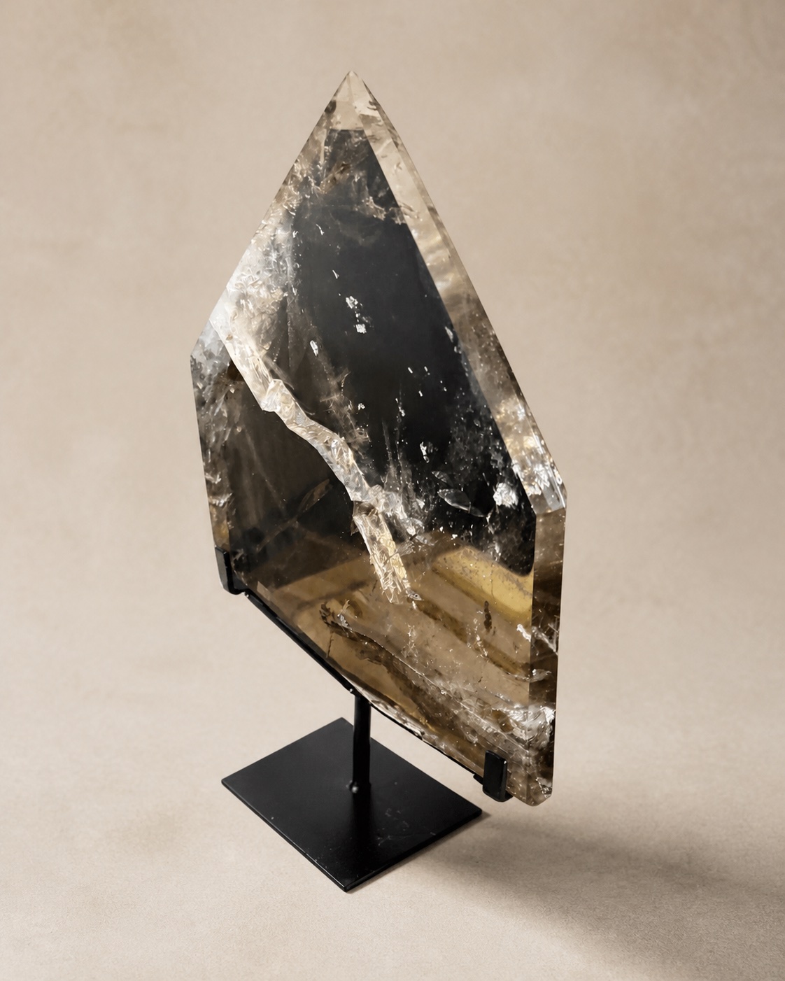 Clear-to-smoky quartz shield-point sculpture displayed on a dark pedestal